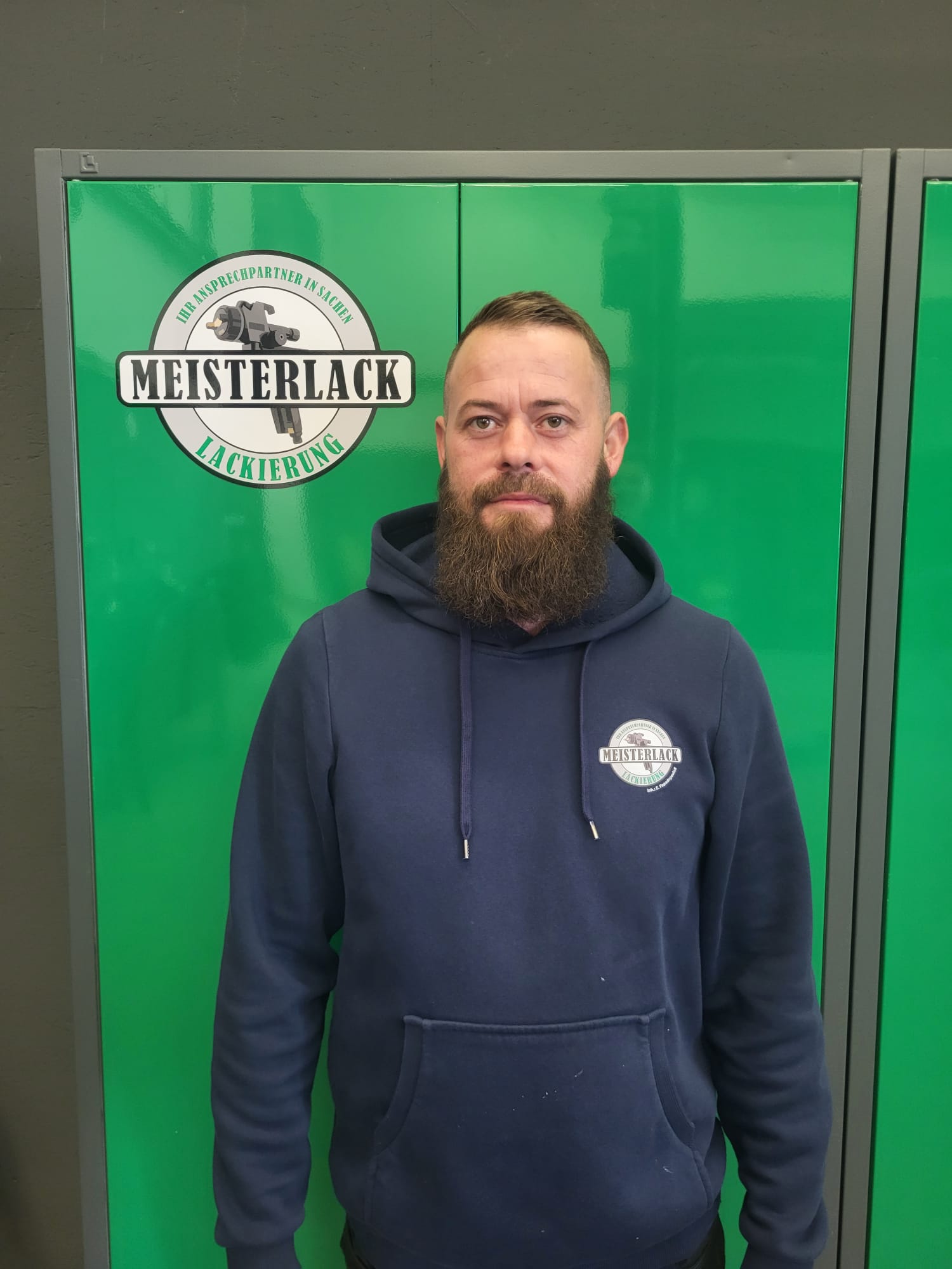 Eric Papadopoulos vor dem Meisterlack Werkstattlogo